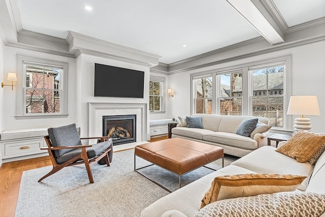 living room featuring beamed ceiling, ornamental molding, light hardwood / wood-style floors, and a wealth of natural light