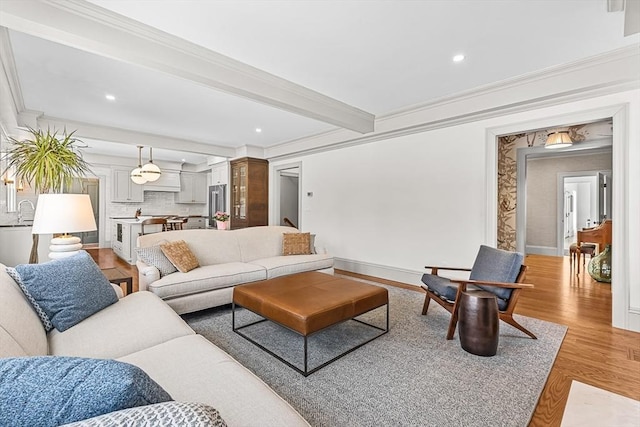 living room featuring beamed ceiling, ornamental molding, and light hardwood / wood-style floors