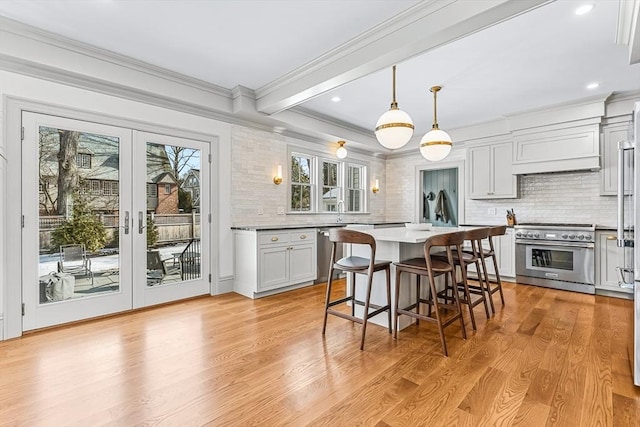 kitchen with pendant lighting, white cabinetry, a kitchen bar, stainless steel appliances, and french doors