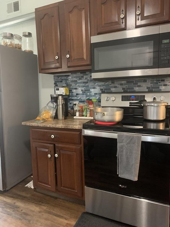 295 Grove St, Brockton, MA 02302 - kitchen featuring appliances with stainless steel finishes, wood finished floors, decorative backsplash, and light countertops