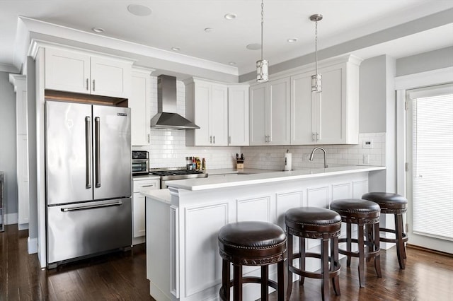 kitchen featuring wall chimney exhaust hood, decorative light fixtures, high quality fridge, kitchen peninsula, and white cabinets