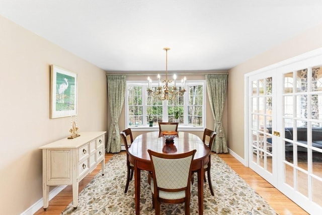 dining space featuring a chandelier, light wood finished floors, and baseboards