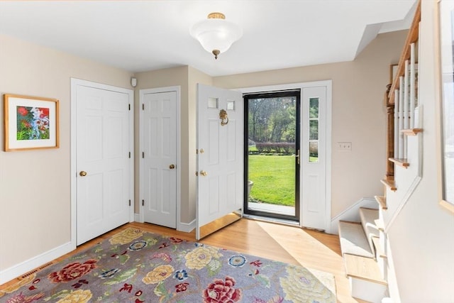 entryway featuring baseboards, light wood-style flooring, and stairs