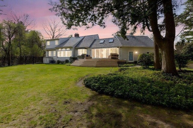 back of property featuring a yard, a chimney, fence, and a deck