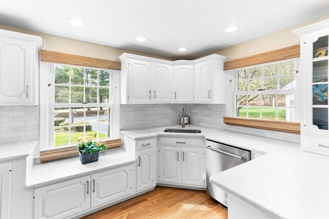 kitchen featuring stainless steel dishwasher, white cabinetry, a sink, and light countertops