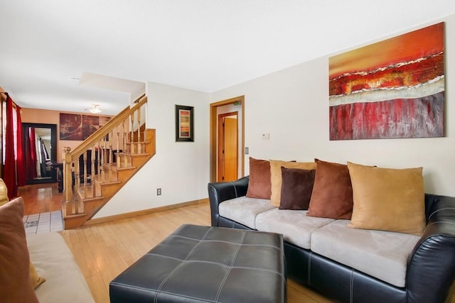 living room with stairs, light wood-style flooring, and baseboards