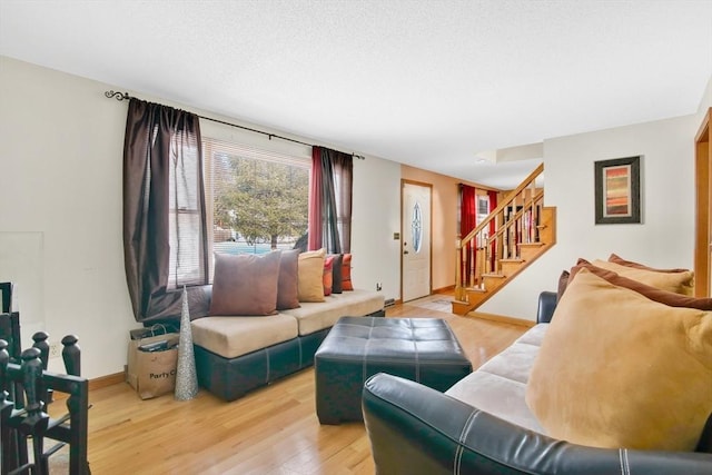 living room featuring baseboards, stairway, and wood finished floors