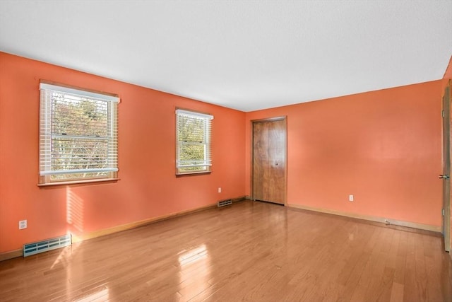 unfurnished room featuring light wood finished floors, baseboards, and visible vents