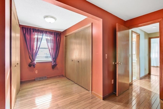 interior space with light wood finished floors, visible vents, and baseboards