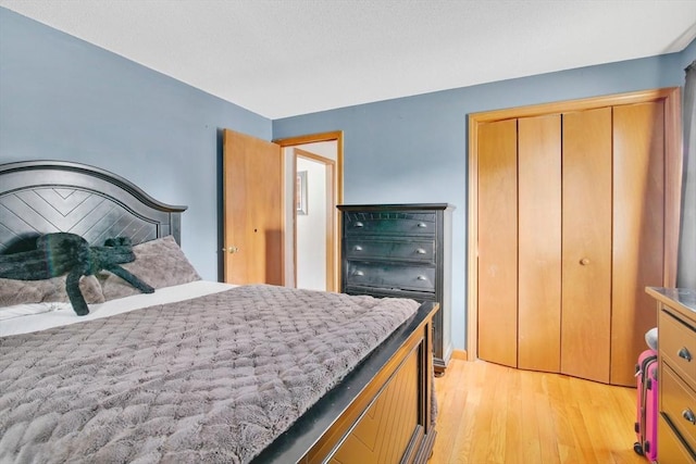 bedroom with light wood finished floors and a closet