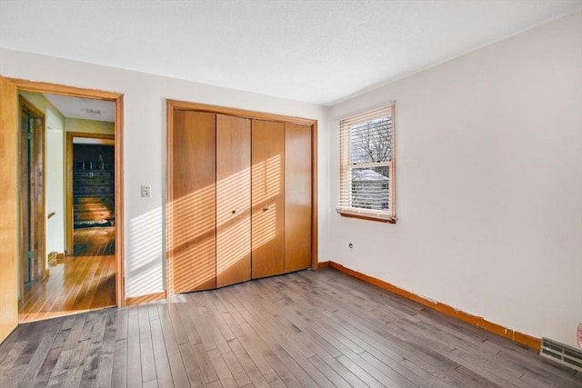 unfurnished bedroom featuring light wood finished floors, a closet, visible vents, and baseboards