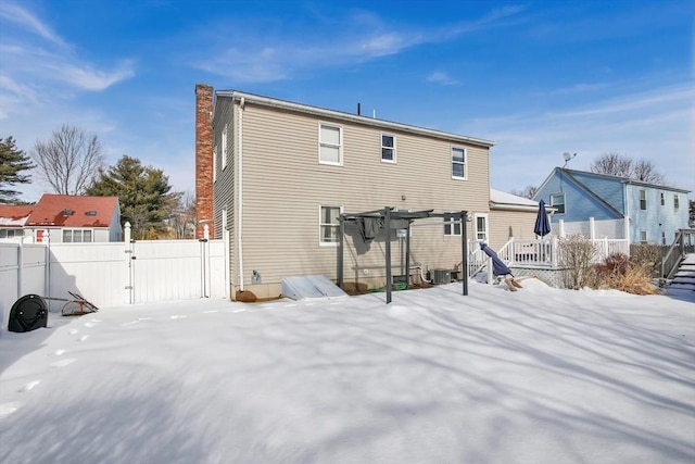 snow covered property with a chimney, a gate, fence, and a pergola