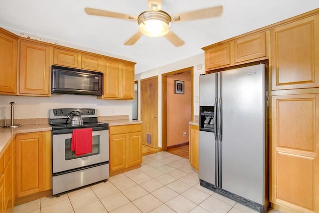 kitchen with appliances with stainless steel finishes, light tile patterned flooring, light countertops, and a ceiling fan