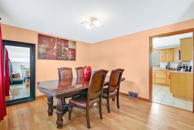 dining room featuring light wood-style flooring, visible vents, and baseboards