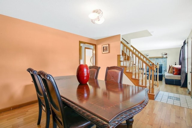 dining space with light wood finished floors, stairway, and baseboards