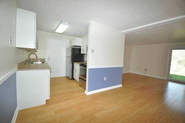 kitchen with a sink, light wood finished floors, light countertops, stainless steel appliances, and white cabinetry