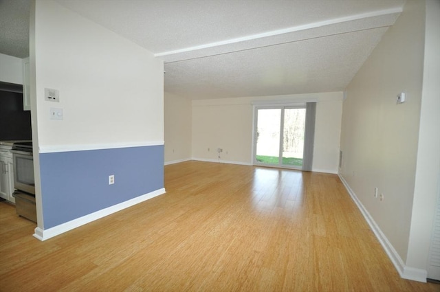 unfurnished room featuring baseboards, light wood-type flooring, and a textured ceiling