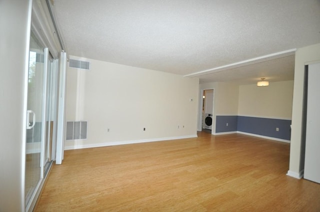 spare room with visible vents, a textured ceiling, washer / dryer, and light wood-type flooring
