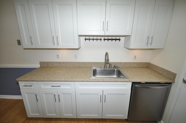 kitchen with light stone countertops, dishwasher, a sink, baseboards, and white cabinets