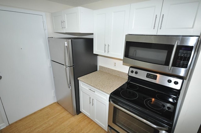 kitchen featuring light stone counters, appliances with stainless steel finishes, white cabinets, and light wood-style flooring