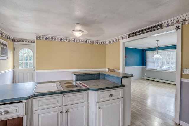 kitchen featuring plenty of natural light, white cabinets, pendant lighting, and a baseboard heating unit