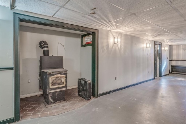 basement with a drop ceiling and a wood stove