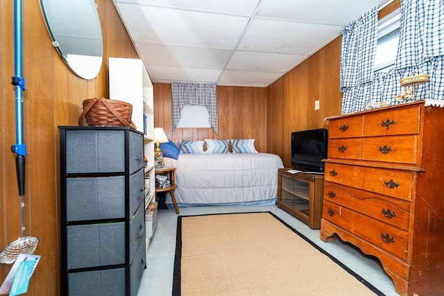 bedroom featuring a drop ceiling and wooden walls