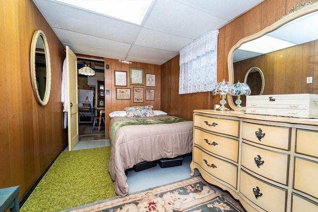 bedroom with a paneled ceiling and wooden walls