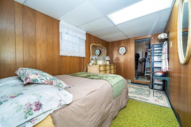 bedroom featuring wooden walls, a closet, and a drop ceiling