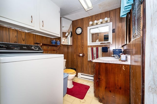 laundry room featuring wood walls, washer / clothes dryer, sink, and a baseboard heating unit