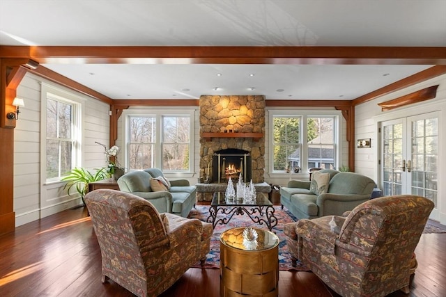 living area featuring a stone fireplace, a healthy amount of sunlight, wood walls, and wood-type flooring