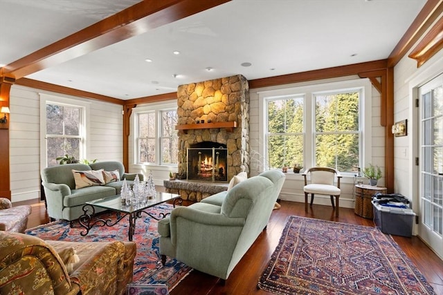 living room with beamed ceiling, a stone fireplace, wooden walls, and wood-type flooring