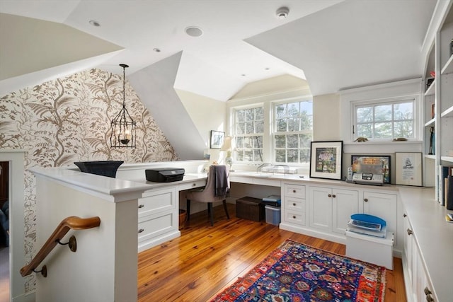 office featuring lofted ceiling, light wood-style flooring, and built in desk