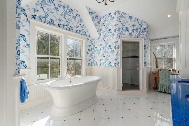 full bathroom with wallpapered walls, a freestanding bath, a stall shower, and wainscoting