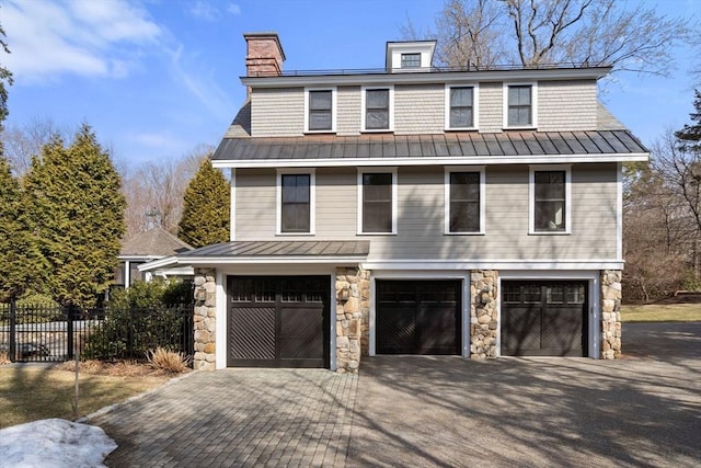 view of front facade featuring a standing seam roof, an attached garage, driveway, and metal roof