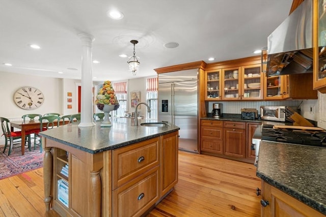 kitchen featuring a sink, wall chimney range hood, decorative columns, and stainless steel appliances