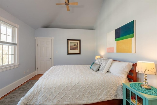 bedroom with vaulted ceiling, ceiling fan, wood-type flooring, and multiple windows