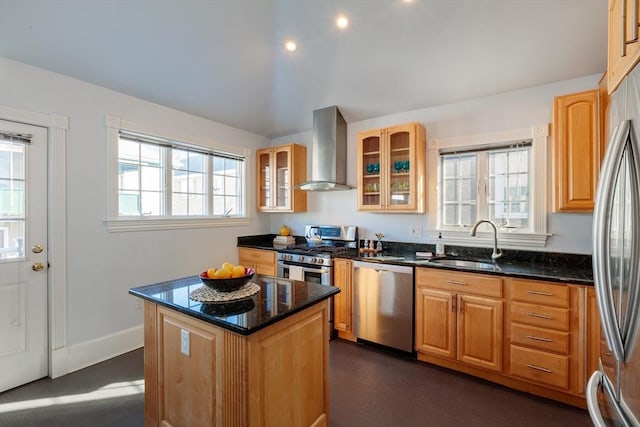 kitchen with appliances with stainless steel finishes, wall chimney exhaust hood, a kitchen island, dark stone countertops, and sink