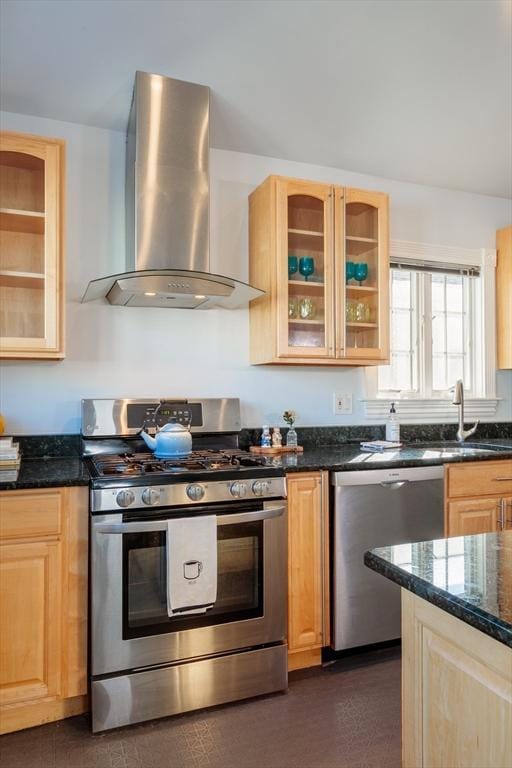 kitchen with exhaust hood, light brown cabinetry, dark stone counters, sink, and stainless steel appliances