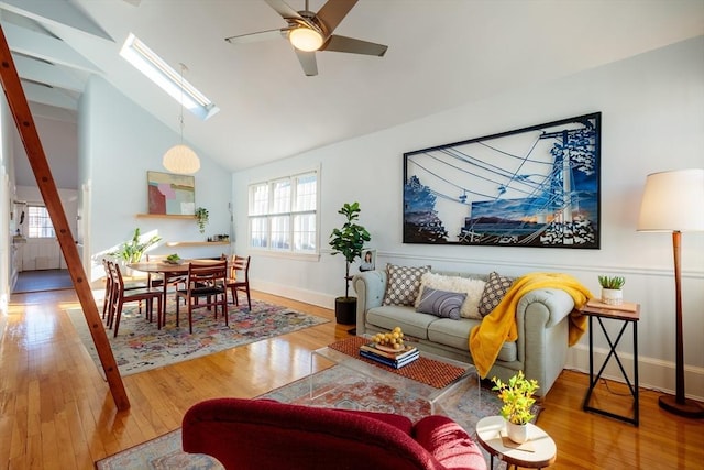 living room featuring hardwood / wood-style flooring, lofted ceiling with skylight, and ceiling fan