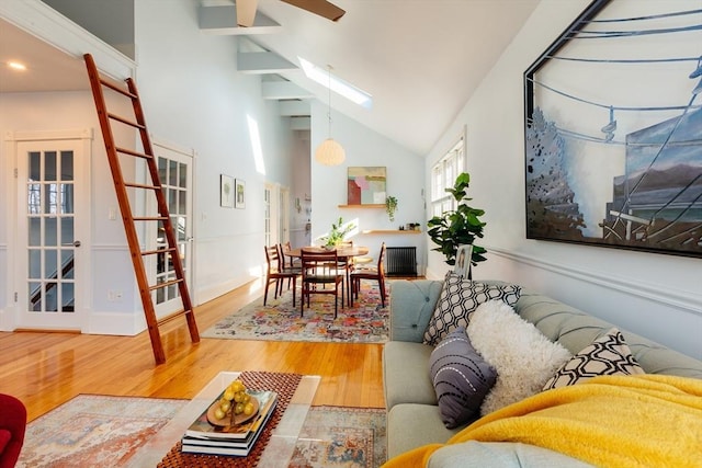 living room with high vaulted ceiling, wood-type flooring, and a skylight