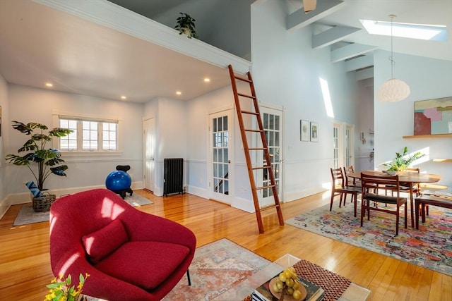 living room featuring hardwood / wood-style flooring, a towering ceiling, a skylight, and french doors