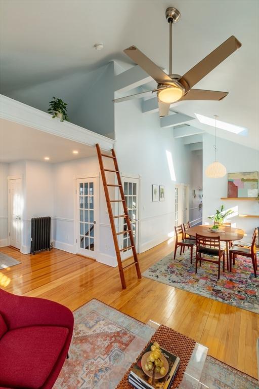 living room with hardwood / wood-style flooring, high vaulted ceiling, ceiling fan, and radiator