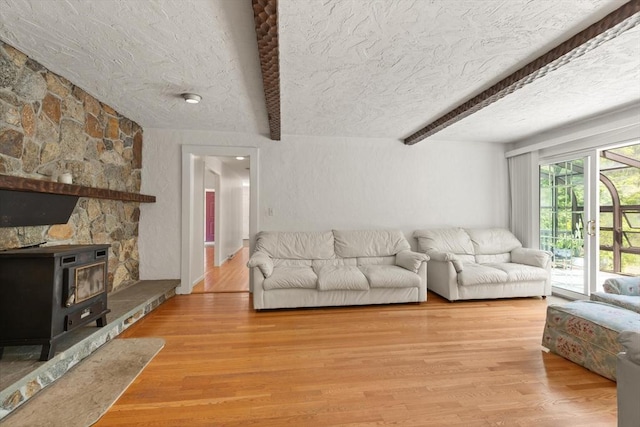 12 Queens Cir, Sharon, MA 02067 - living area featuring beam ceiling, a wood stove, a textured ceiling, and wood finished floors