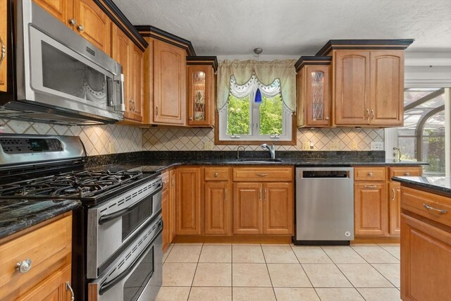 12 Queens Cir, Sharon, MA 02067 - kitchen featuring appliances with stainless steel finishes, glass insert cabinets, a sink, light tile patterned flooring, and tasteful backsplash