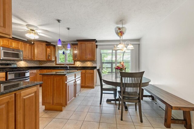 12 Queens Cir, Sharon, MA 02067 - kitchen with stainless steel appliances, backsplash, brown cabinets, a center island, and decorative light fixtures