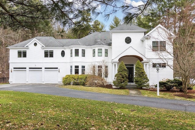 traditional-style house featuring a garage, driveway, and a front lawn