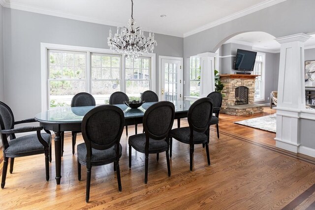 dining area with light wood-style floors, a wealth of natural light, and a stone fireplace