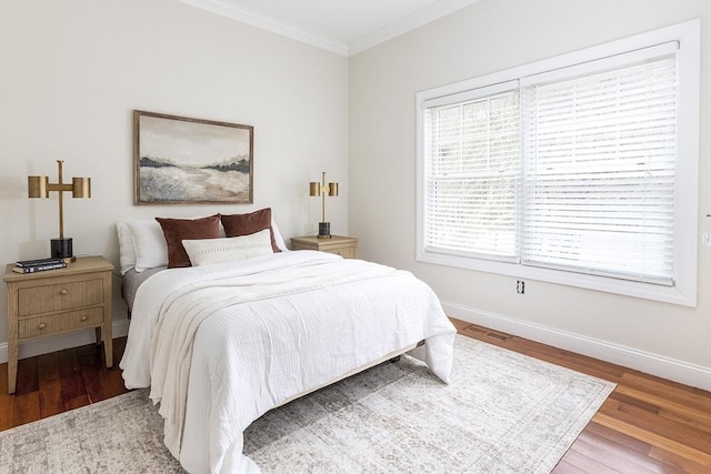 bedroom with visible vents, crown molding, baseboards, and wood finished floors