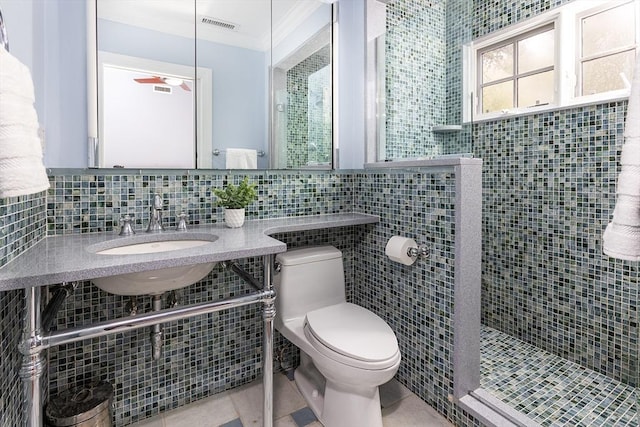 bathroom featuring toilet, ornamental molding, tile patterned floors, a shower stall, and a sink